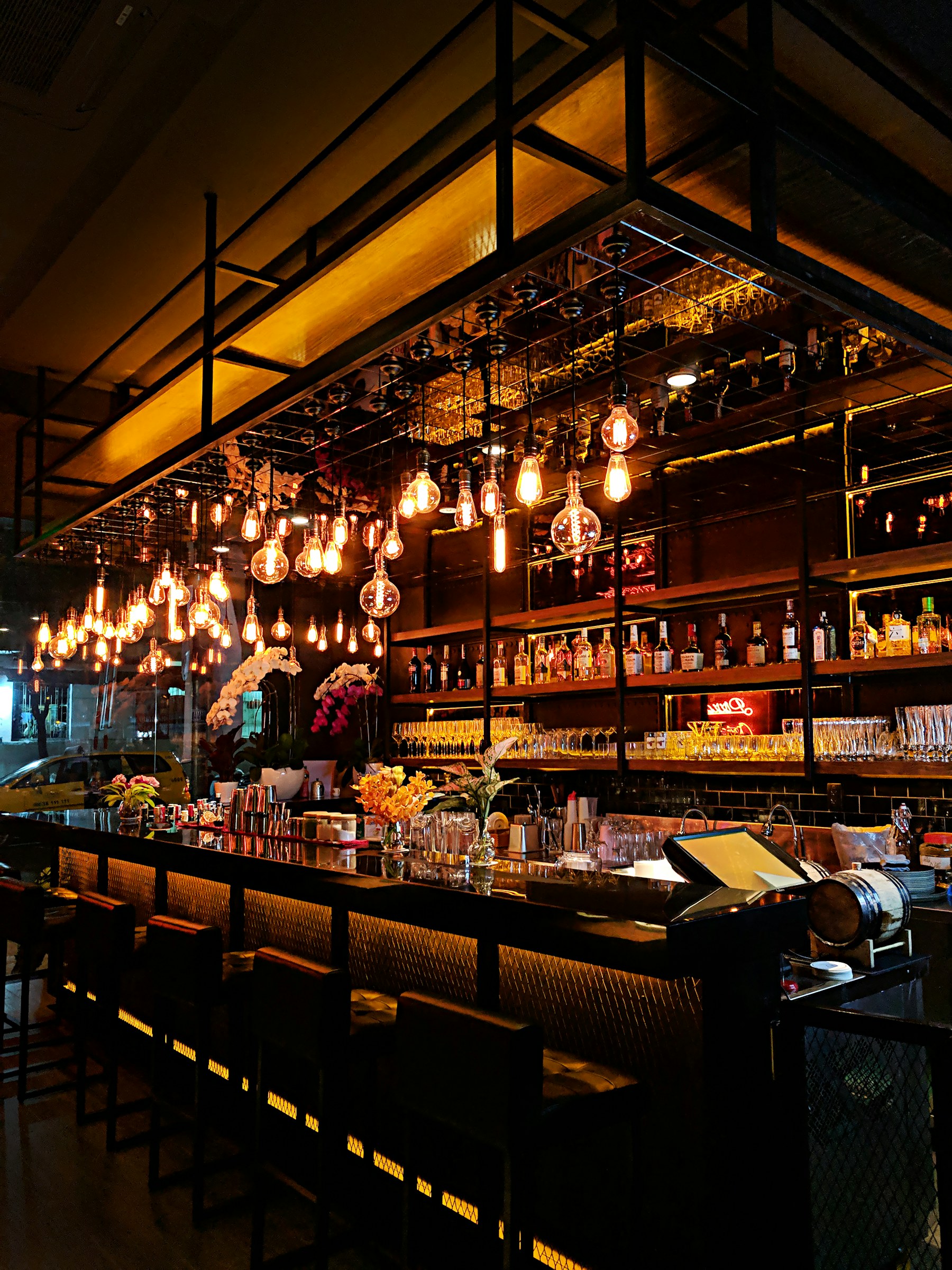 A warmly lit bar interior with hanging Edison bulbs and a polished bar counter.
